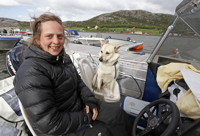 Fra kapteinplassen styrer Kari-Anne Nilsen skuta mot Røst, mens buhunden Buster er copilot og har fast plass i den andre stolen.