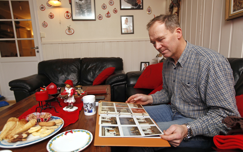 Raymond ser i et gammelt album, med bilder fra oppveksten på Frøya.