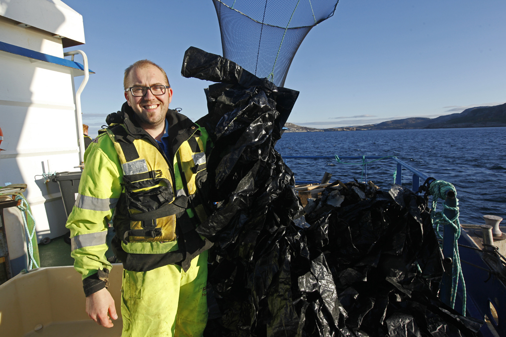 Disse plastremsene som Marius Olsen viser fram, brukes som skjul for leppefisken. De gjør at fisken trives i merdene og at laksen kan komme dit for å bli kvitt lusa.