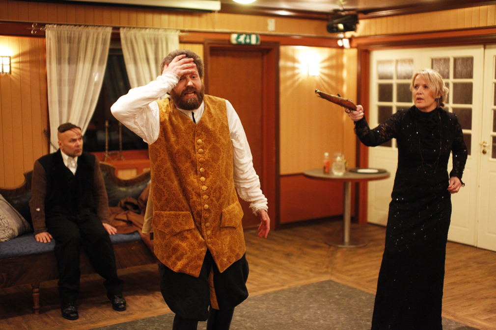 Fru Popova (Bente Kløven) utfordrer en noe motvillig Oscar Løvenskjold (Børre Sivertsen) til duell. Tjener Viktor (Knut Johnsrud) er livredd tilskuer.