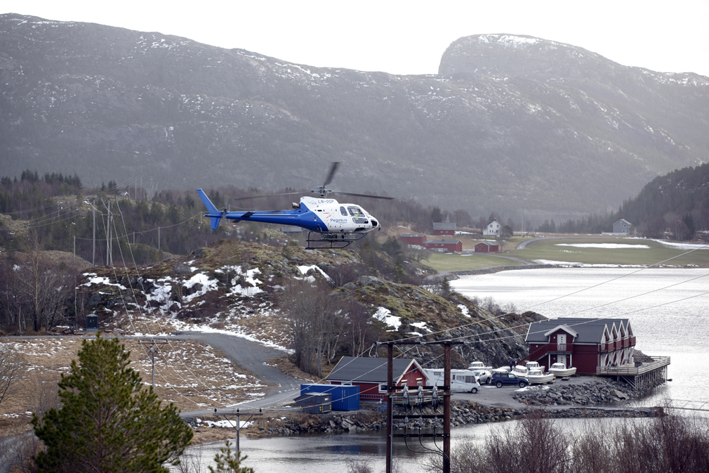 Helikopteret flyr lavt og krysser linja slik at mastene skal fotograferes fra alle sider. Her fra Storlavika, med Stamnes i bakgrunnen.