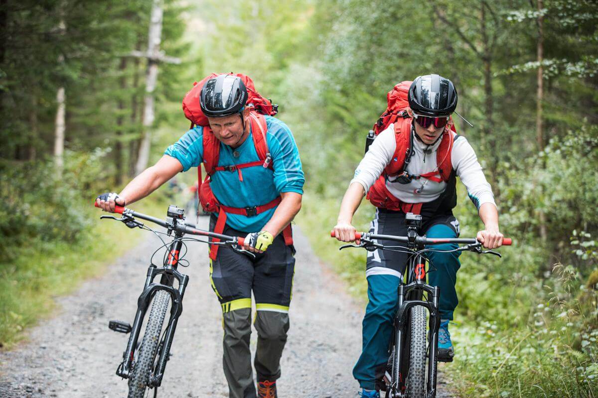 Steffen Iversen og Astrid Uhrenholdt Jacobsen kjemper seg fram på sykkeletappen gjennom Flatanger i femte episode av "71 grader nord - Norges tøffeste kjendis". (Foto: Haakon Lundkvist)