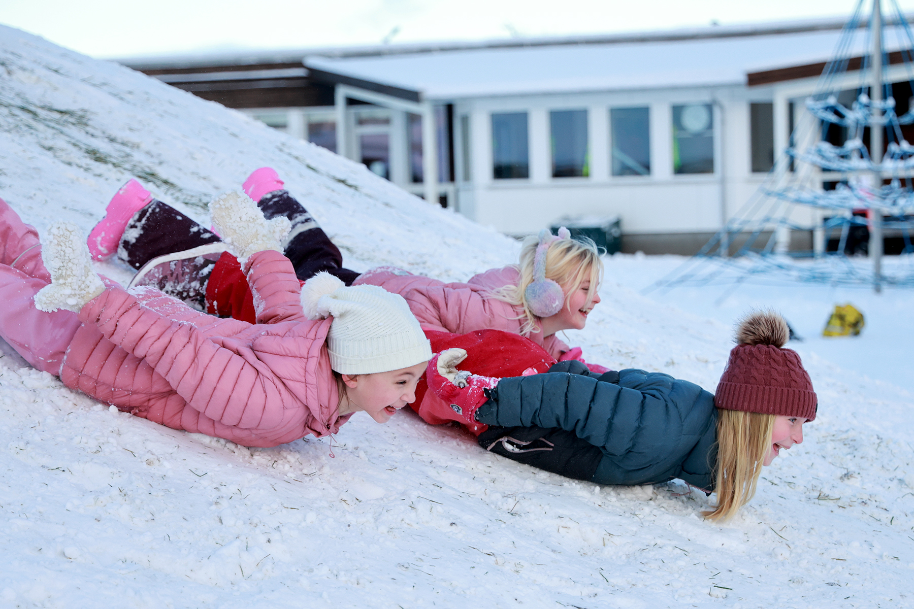 Lotta, Nora og Jenny i full fart p&aring; magen nedover akebakken.