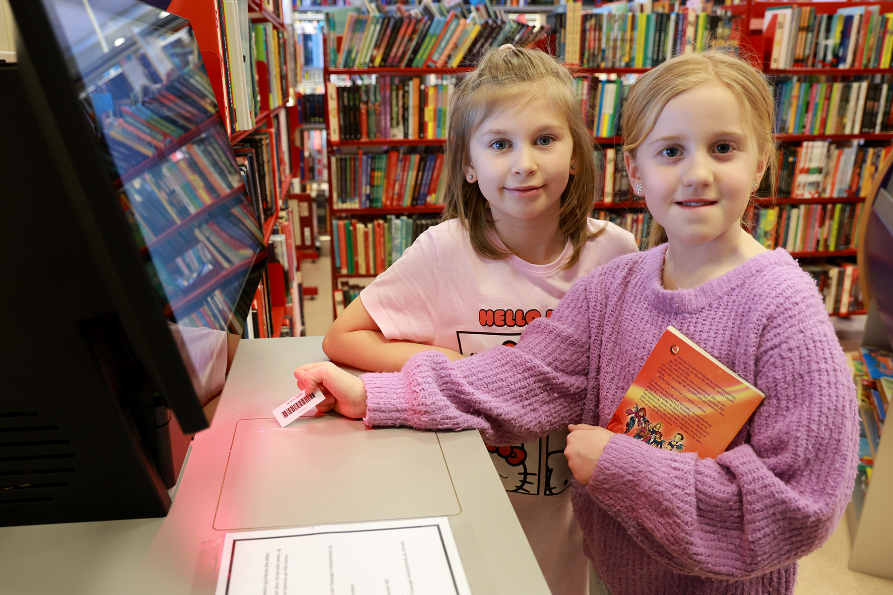 Liza (til venstre) og Stella har fått nye lånekort, og kan nå registrere lån og innleveringer selv i automaten på biblioteket.