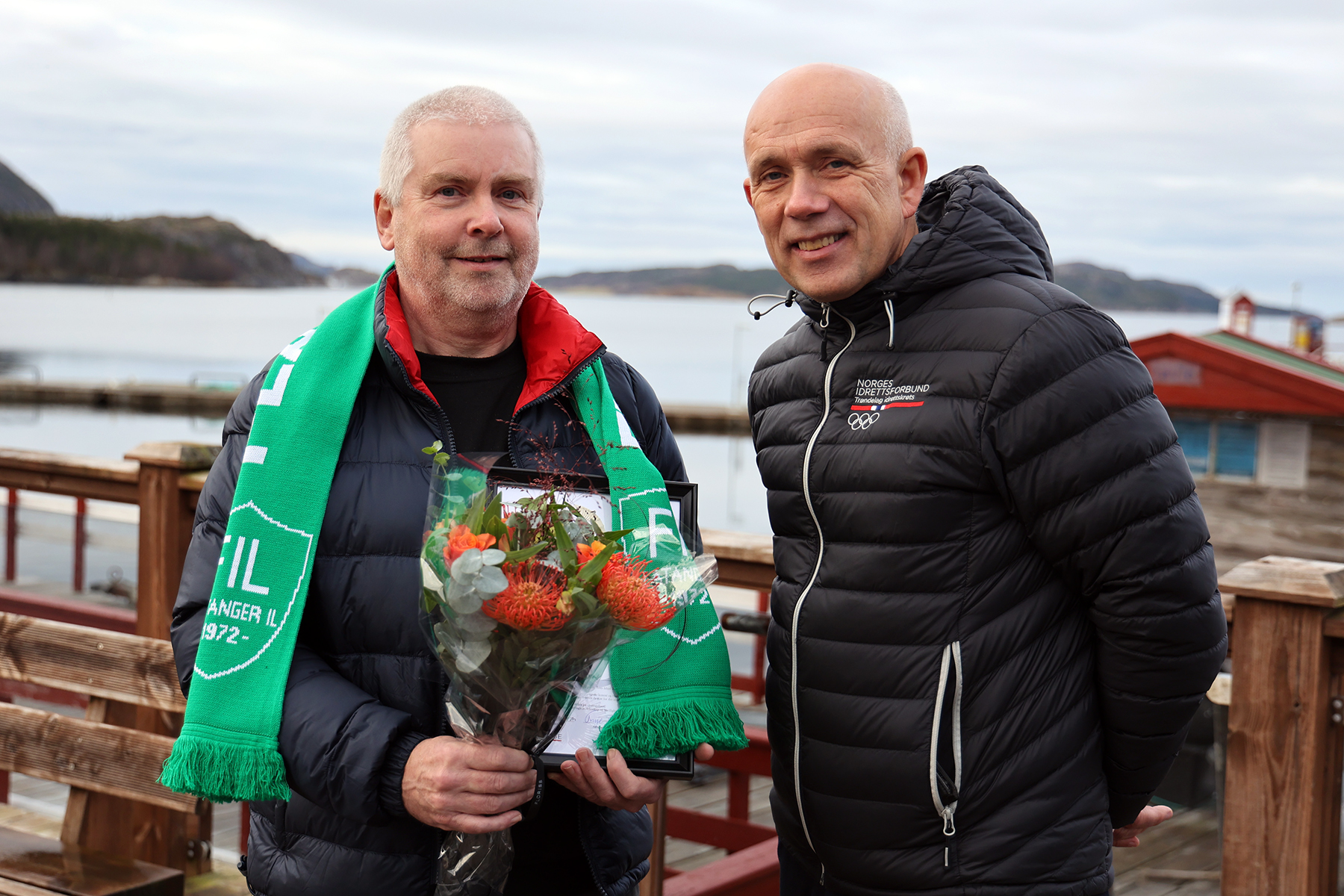 Kjell Bjarne Helland (til høyre) i Idrettsforbundet overrakte blomster, diplom og 5000 kroner til Håvard Angen Haarstadstrand, som nå er Trøndelags kandidat til ildsjelprisen.