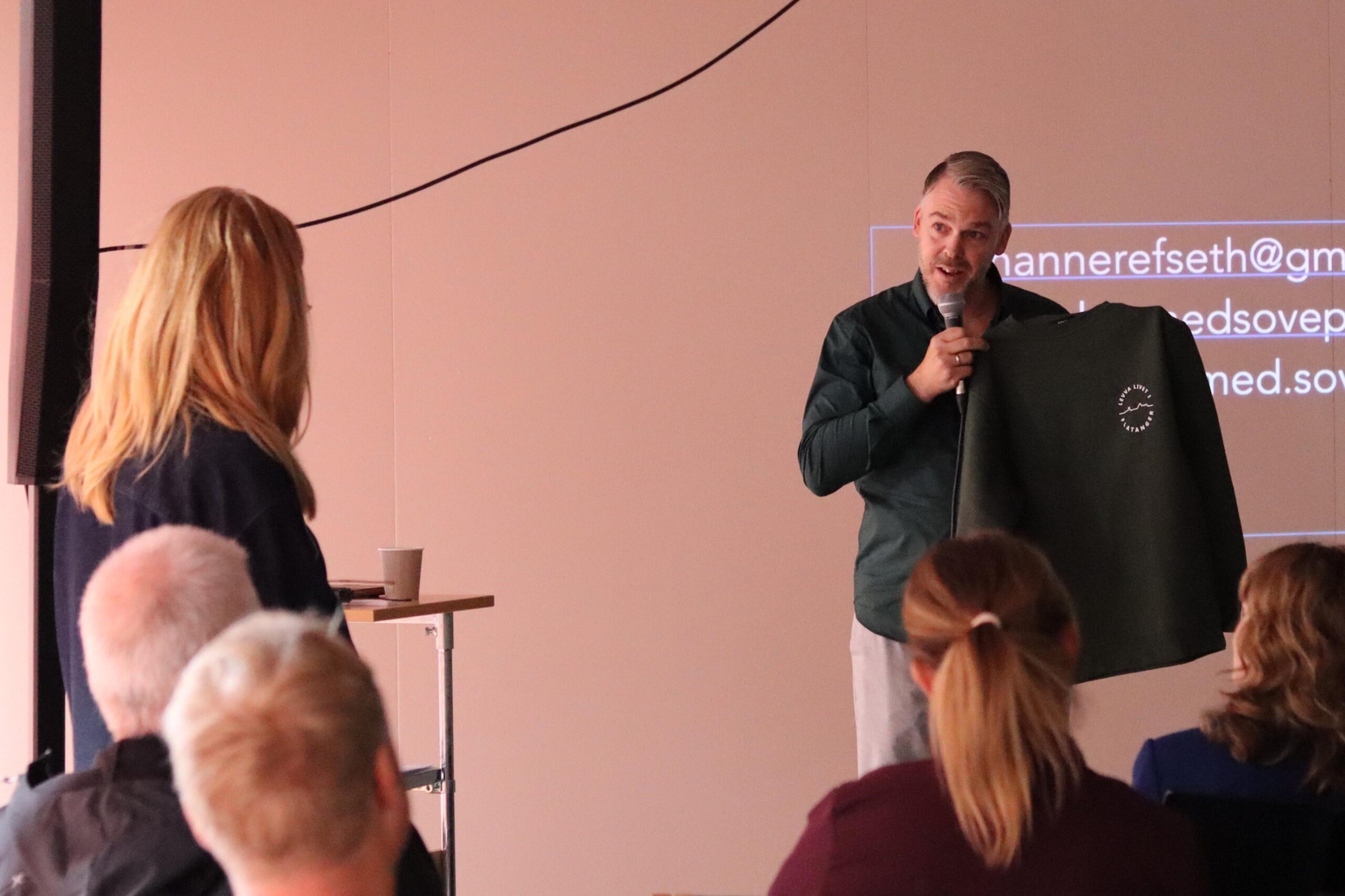 Kommunedirekt&oslash;r Knut Storeide ga psykologen en genser med "Levva livet i Flatanger" - og fri adgang til alle fjelltoppene i kommunen. 