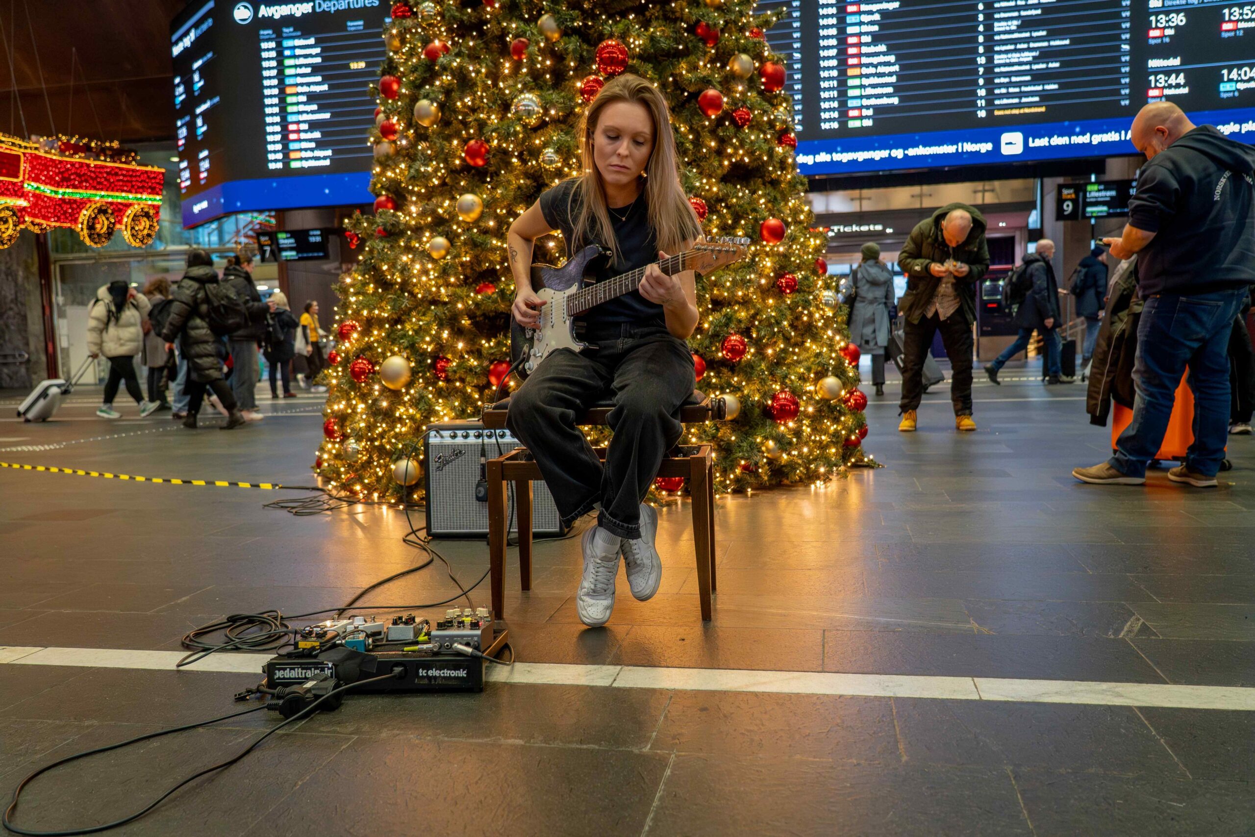 Tora Dahle Aagård spiller mens julerushet passerer på alle kanter på Oslo S. Foto: NRK.