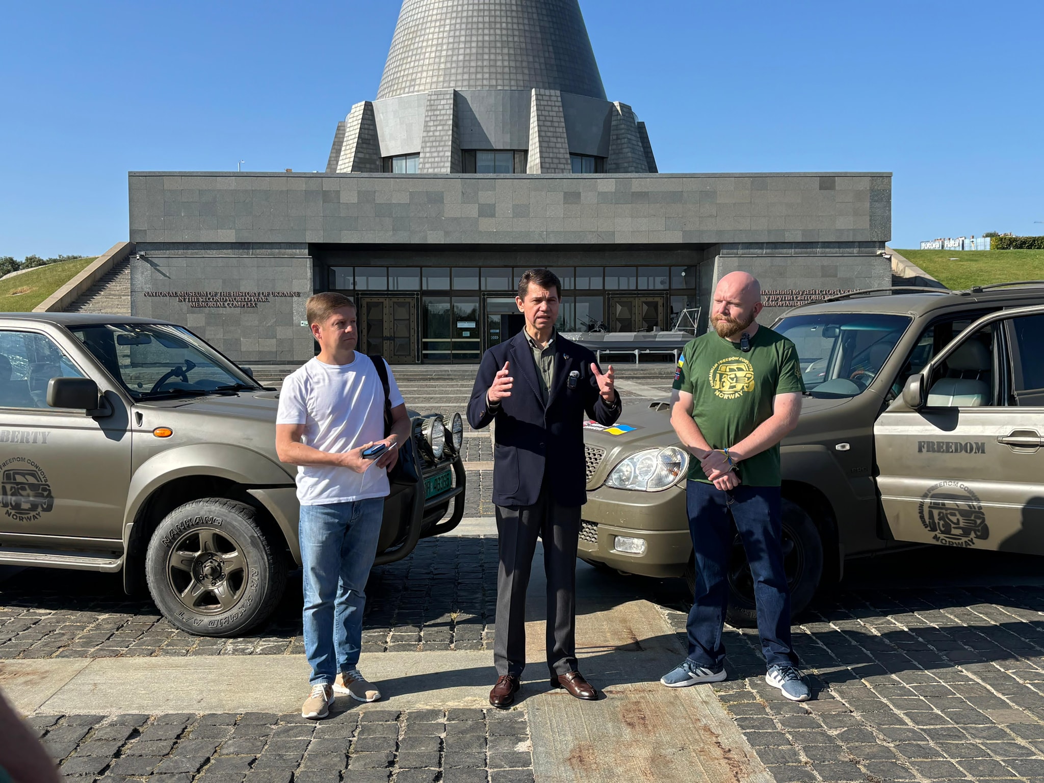 Viseutenriksminister Olexandr Mischenko (i midten) tok imot bilene som ble overlevert ved Mor Ukraina-monumentet av konvoi-leder Lars P. Solås (Foto: UFC)